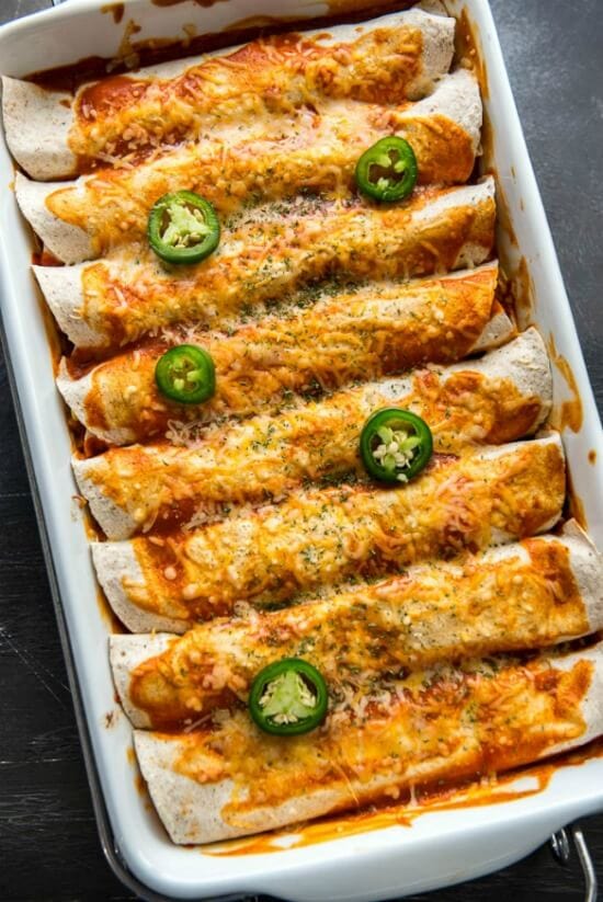 Overhead view of enchiladas in a 9x13 pan garnished with jalapeños