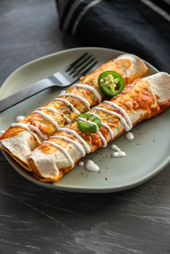 Two enchiladas on a plate with a fork