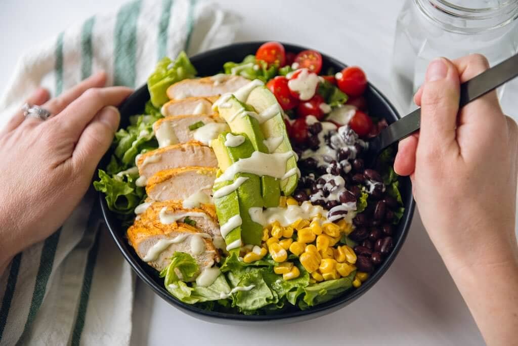 Woman eating a southwest chicken salad with hands holding fork