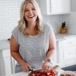 Blonde hair woman cutting strawberries in a white kitchen
