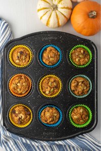 Healthy Pumpkin muffins in a black muffin tin with muffins and a napkin