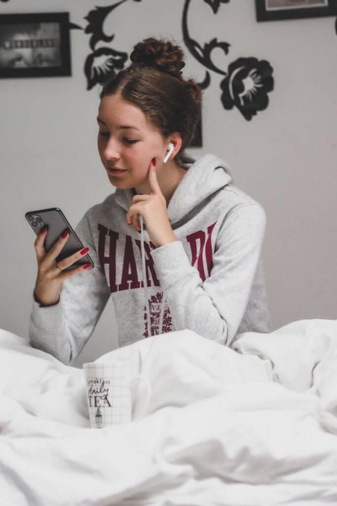  a girl playing on her phone in her bed