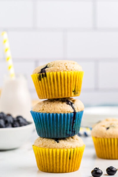 A stack of 3 lemon blueberry muffins with yellow and blue liners